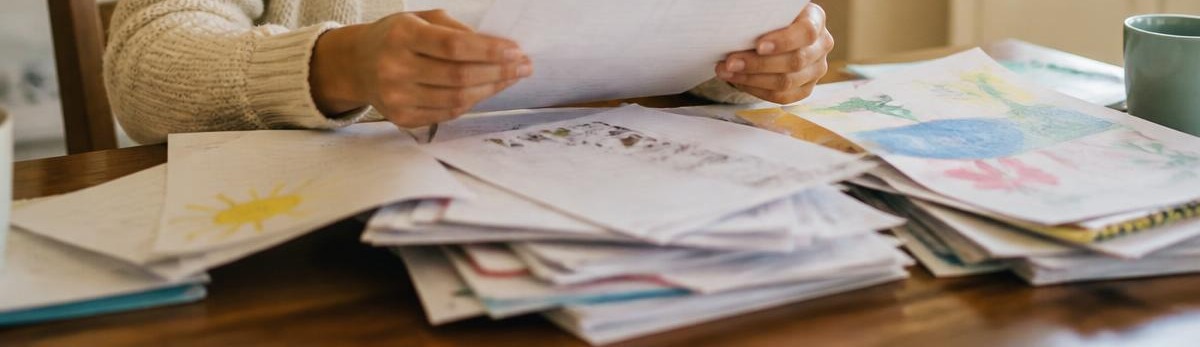 Chaya sorting through a pile of children's school papers at her kitchen table
